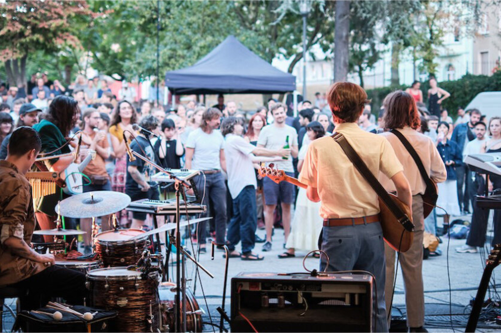 Musiker*innen geben ein Konzert auf dem Ebertplatz. Vor der Bühne stehen Menschen., Link auf Karten zu Kultur und Geschichte