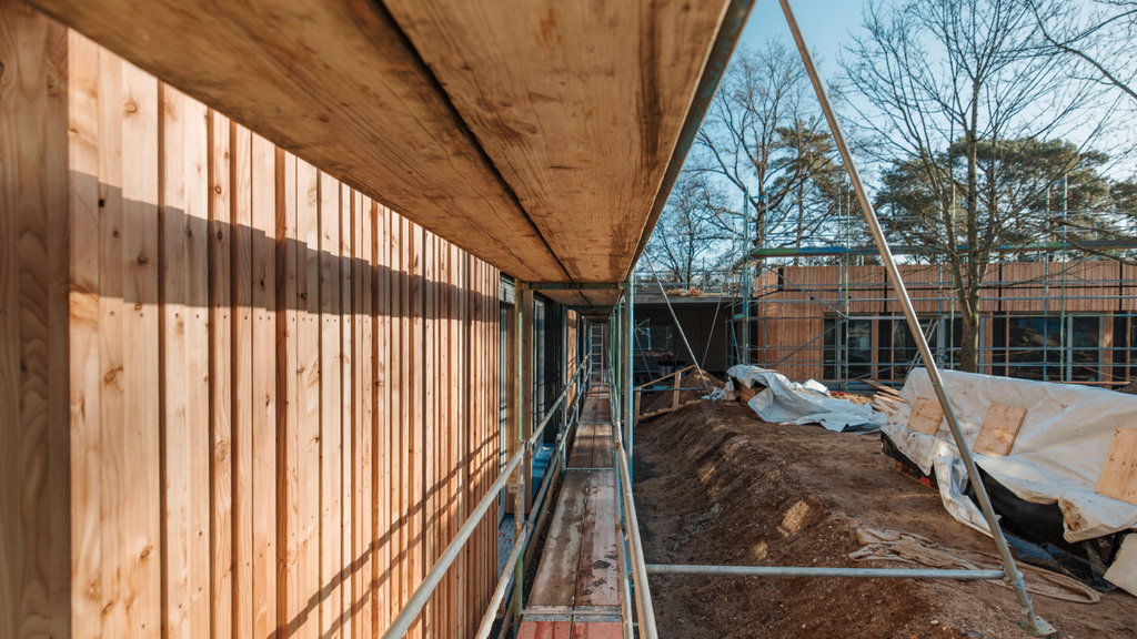 Blick durch das Baugerüst vor der Fassade aus Lärchen-Holz mit dem künftigen Schülerzentrum