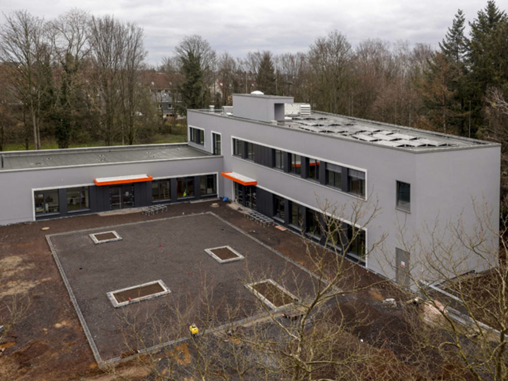 Der Erweiterungsbau vom Altbau aus betrachtet kurz vor Fertigstellung und Gestaltung der Außenanlagen mit Baumpflanzungen, Link auf Erweiterungsbau Gesamtschule Dellbrücker Mauspfad - Stadt Köln