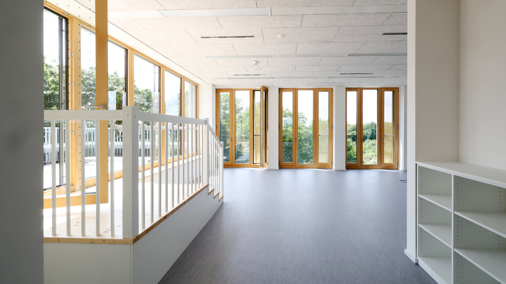 Das so genannte Selbstlernzentrum mit bodentiefen Fenster ringsherum mit Rahmen aus hellem Holz. Eine Empore führt einige Stufen hoch auf eine kleine Dachterrasse.