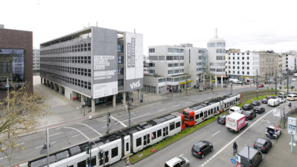 vierspurige Cäcilienstraße, im Hintergrund die Textilfassade am Gebäude der Volkshochschule, Link auf Umwelt-Pilotprojekt für saubere Luft - Stadt Köln