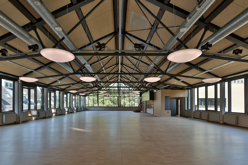 Die neue Mensa dient auch als Veranstaltungsort. Ein besonderer Akzent sind die sichtbaren Stahlfachwerkträger im offenen Dachraum.