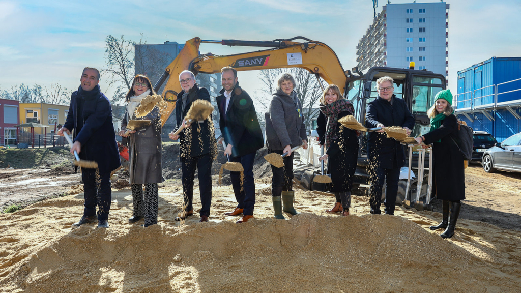 Bethan Ciftci (geschäftsführender Gesellschafter des Generalbauunternehmens Lühnbau GmbH & Co. KG), Petra Rinnenburger (Technische Betriebsleitung Gebäudewirtschaft), Markus Greitemann (Baudezernent), Robert Voigtsberger (Schuldezernent), Dr. Diana Siebert (Bezirksbürgermeisterin Nippes), Anne Lena Ritter (Leiterin des Amtes für Schulentwicklung), Christian Fensterer (Architekt) und Johanna Schubert (Schulleitung der Montessori-Grundschule Gilbachstraße) beim ersten Spatenstich vor der Baugrube
