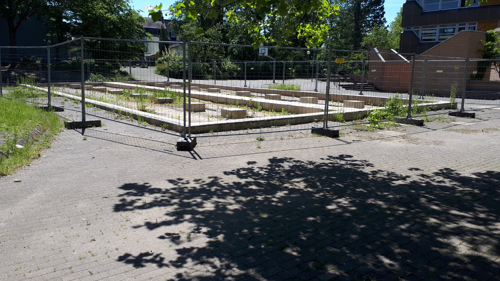 Eingezäunte Entsiegelungsfläche auf dem Schulhof vor den Pflanzarbeiten