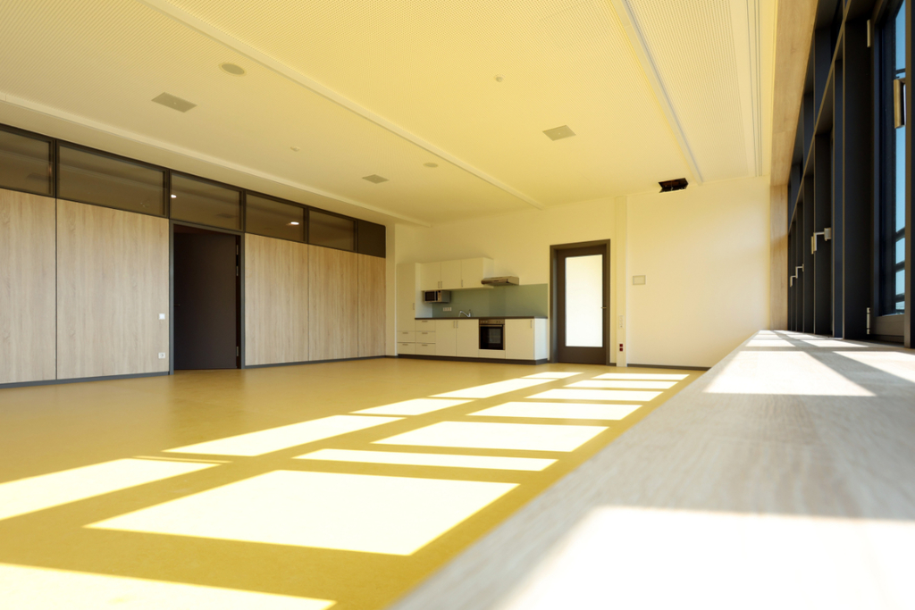 Heller Mehrzweckraum mit gelbem Boden und Küchenzeile in der Förderschule