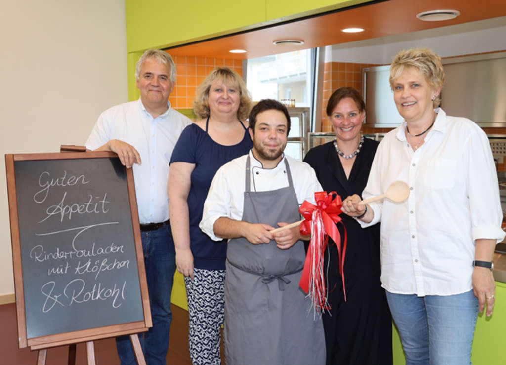 Übergabe eines hölzernen Kochlöffels an den Leiter der Küche