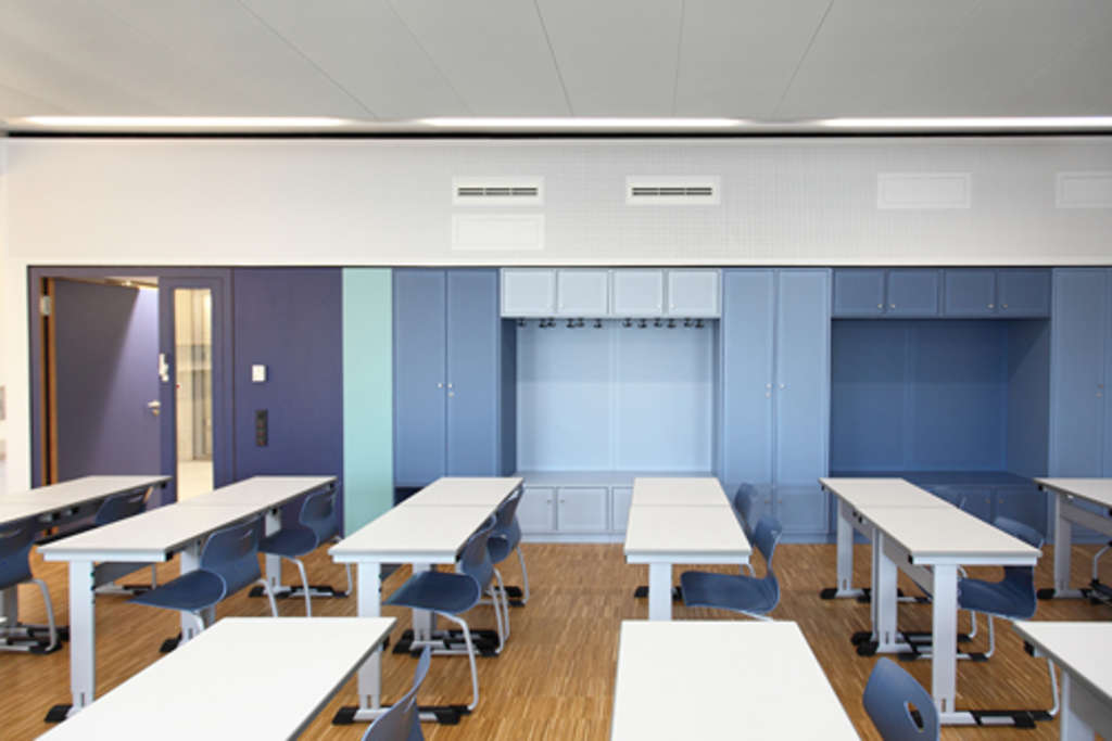 Einbauschrankwände in verschiedenen Blautönen in den Klassen bieten sowohl Raum für Garderobe als auch Schulbladen mit Anschlüssen für Laptops und andere Computertechnik