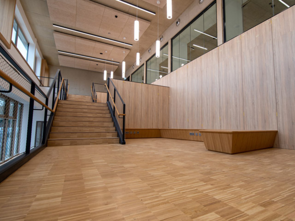 Die so genannte Lerntreppe aus Holz lädt mit Möblierung auf ihren Zwischenebenen zum Verweilen ebenso wie zum kommunikativen Austausch ein.