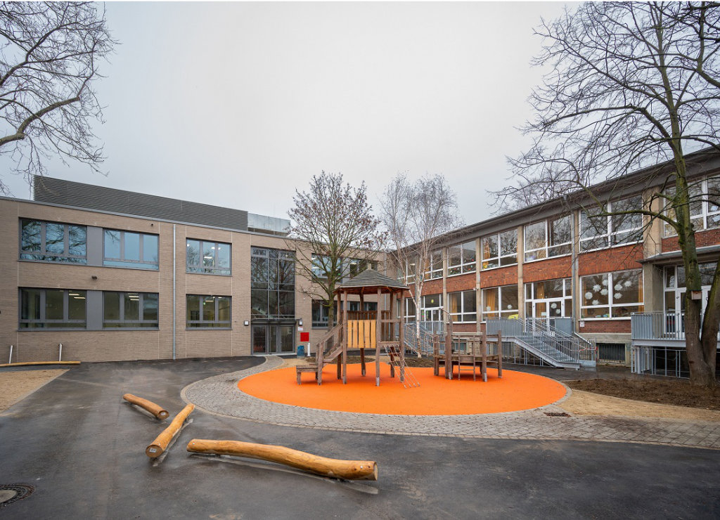 Kletterturm mit Seilbrücke und Rutsche sowie Holz-Balancierstangen auf dem Schulhof