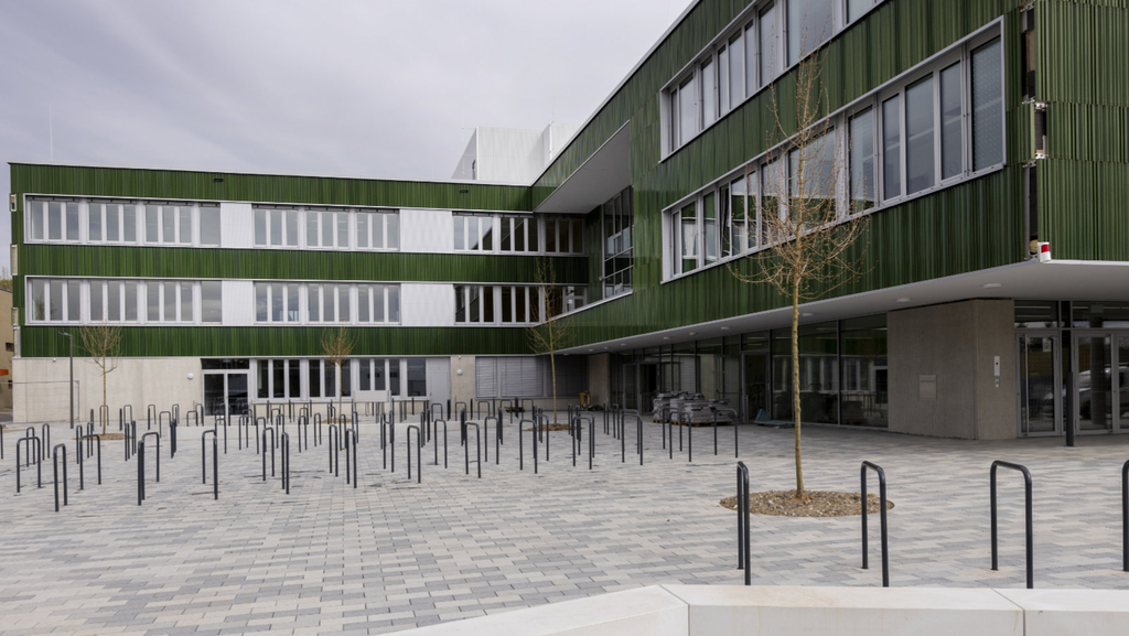 Schulgebäude mit Vorplatz und Schulhof vor der Schule mit Fahrr