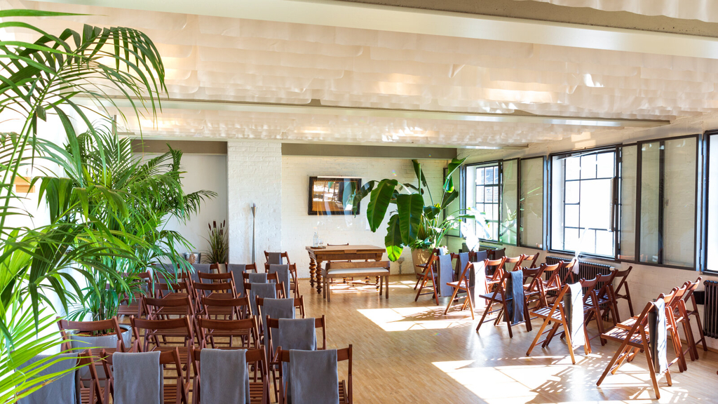 Blick ins Trauzimmer des Kunstsalons. Zu sehen sind Stuhlreihen und eine mit Tüchern bestückte Decke. Ganz vorne befindet sich der Trautisch.