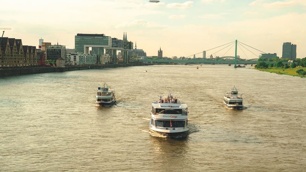 MS RheinCargo, MS RheinPerle und MS RheinTreue auf dem Rhein. Im Hintergrund sind die Krankhäuser, der Dom und die Rheinbrücken zu sehen.