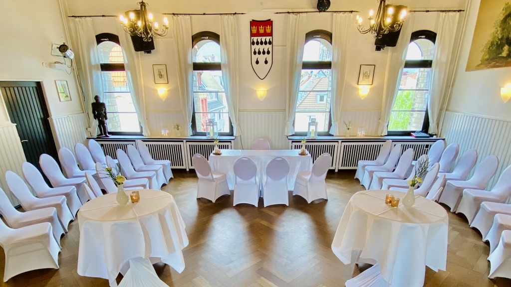 Geschmücktes Trauzimmer im historischen Ambiente der Severinstorburg. Trautisch und Bestuhlung sind mit weißen Hussen versehen.