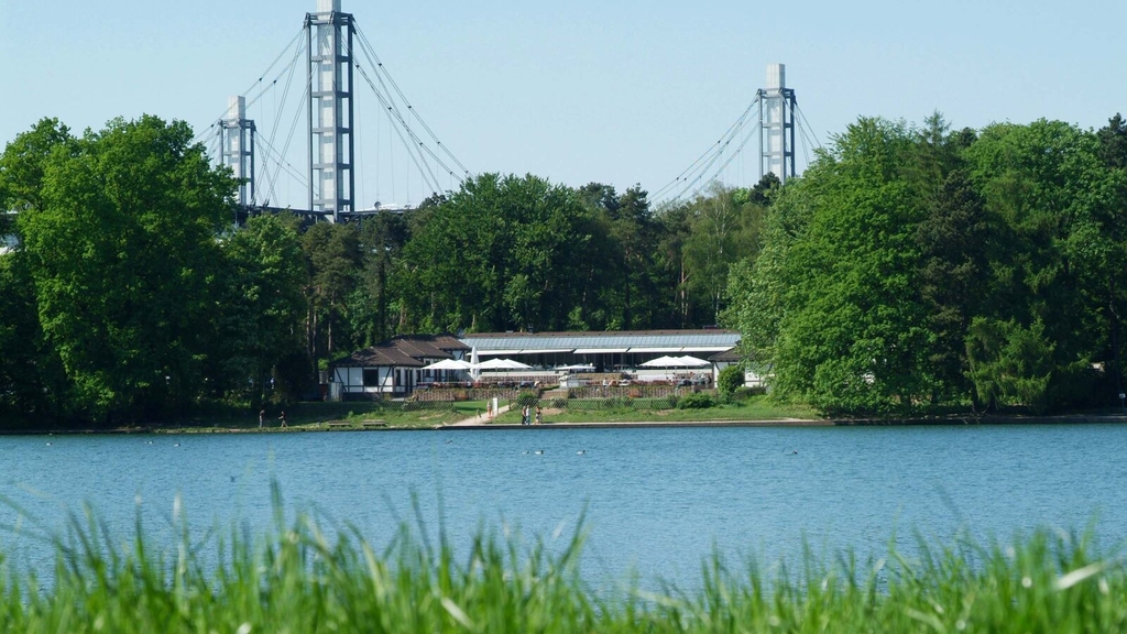 Blick auf die Außenanlage des Club Astoria von der anderen Seite des Adenauerweihers mit dem RheinEnergieSTADION im Hintergrund