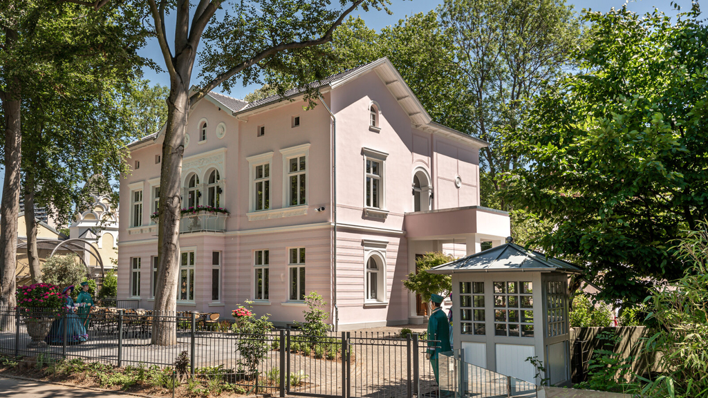 Rosafarbene Villa mit Bäumen umgeben