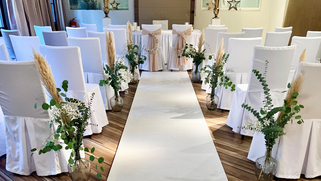 mehrere Stühle mit weiißen Hussen und Blumendekoration.im Trauzimmer des Club Astoria