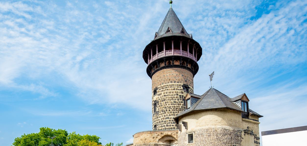 Außenansicht der Ulrepforte. Zu sehen sind histroische Bauwerke in verschiedenen Größen. Als größtes Bauwerk ist die Ulrepforte mit spitzem Dach abgebildet.