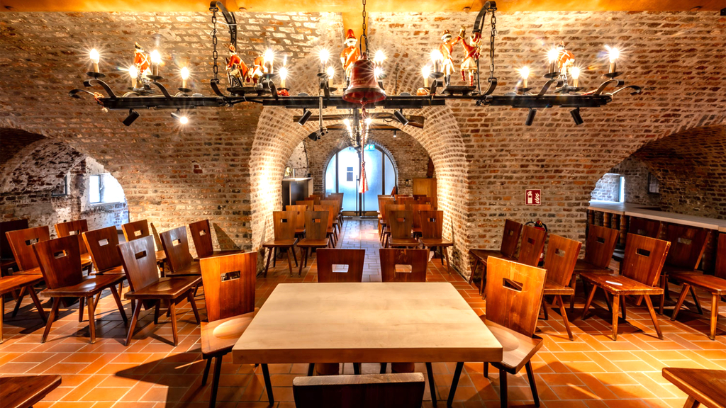 Obere Wachstube: Zu sehen ist ein historisches Gewölbe, in dem im Vordergrund ein Trautisch mit  hölzernen Stühlen für das Hochzeitspaar und Trauzeugen platziert sind. Hinter der Bestuhlung des Paares sowie nach links und rechts sind weitere Holzstühle für Gäste aufgebaut.