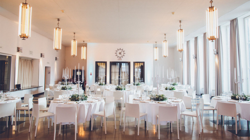 Historische Empfangshalle im Butzweilerhof. In der Halle stehen festlich gedeckte runde Tische mit Stühlen drum herum.tehenm 