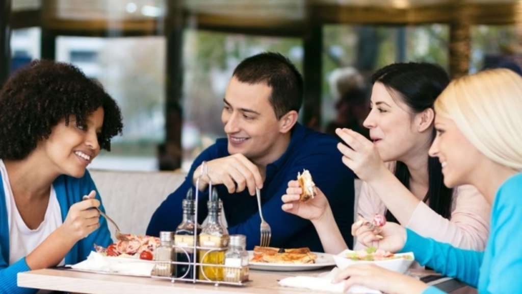 Junge Leute sitzen in einer Gaststätte am Tisch, Link auf Gaststätten