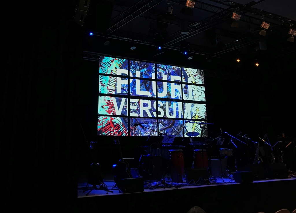 Angestrahltes Bühnenbild mit den Worten "Pluriversum"