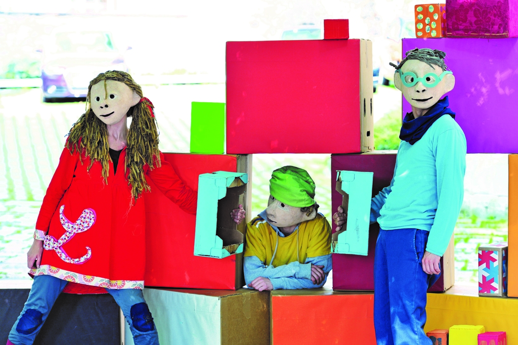 Drei Schauspieler*innen, die als Kinder verkleidet sind und eine Szene spielen