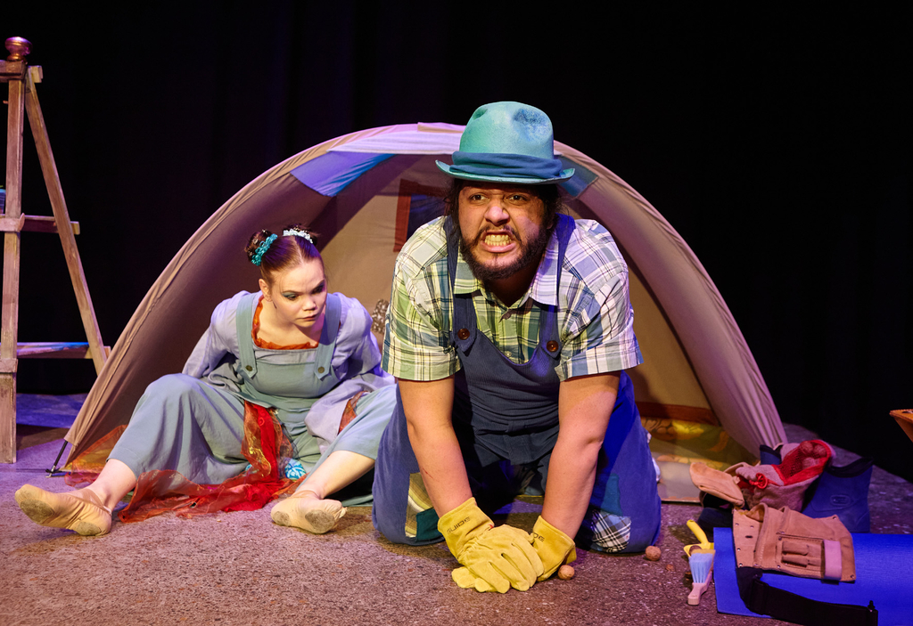 Zwei Schauspieler*innen sitzen auf der Bühne und spiele eine Szene