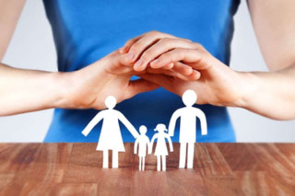 Eine Frau hält ihre Hände über einen Papierschnitt in Form einer Familie, Link auf Informationen zu Vaterschaft, Sorgerecht und Unterhalt