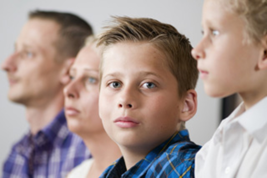 Junge mit im unscharfen Hintergrund aufgereihten Eltern und Bruder, Link auf Beratung für Eltern - Stadt Köln