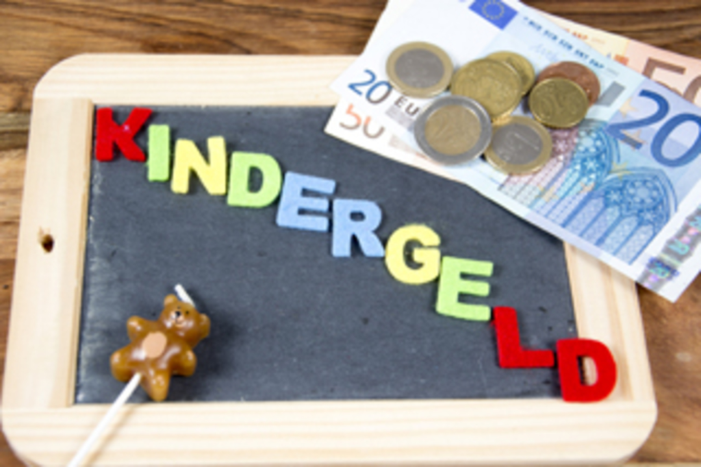 Schiefertafel mit der Aufschrift Kindergeld und Münzgeld im Hintergrund, Link auf Kindergeld
