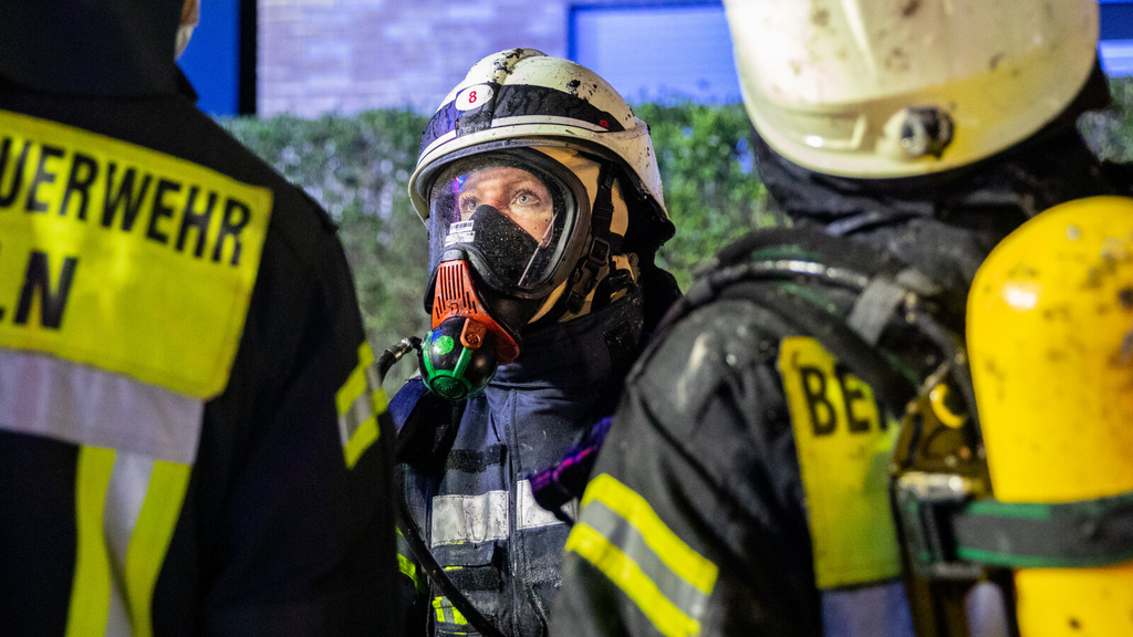 Drei Feuerwehrkräfte, darunter eine Feuerwehrfrau, stehen vor einem gelöschten Haus., Link auf Ausbildung zum*zur Brandmeister*in