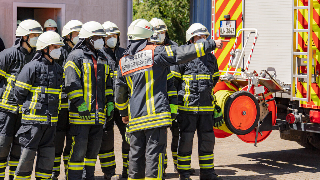 Ein Ausbilder steht vor seinen Auszubildenen und erklärt was zu einem Einsatzfahrzeug.