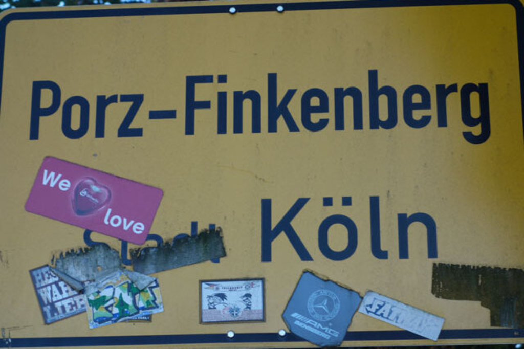 Foto des Ortsschildes Finkenberg mit Aufklebern darauf, Link auf Unternehmen engagiert fürs Veedel - Finkenberg