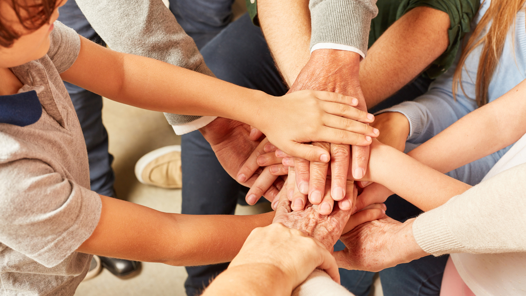 Eine diverse Menschengruppe hat die Hände im Kreis übereinander gelegt., Link auf Engagementmöglichkeiten bei der Stadt Köln - Stadt Köln