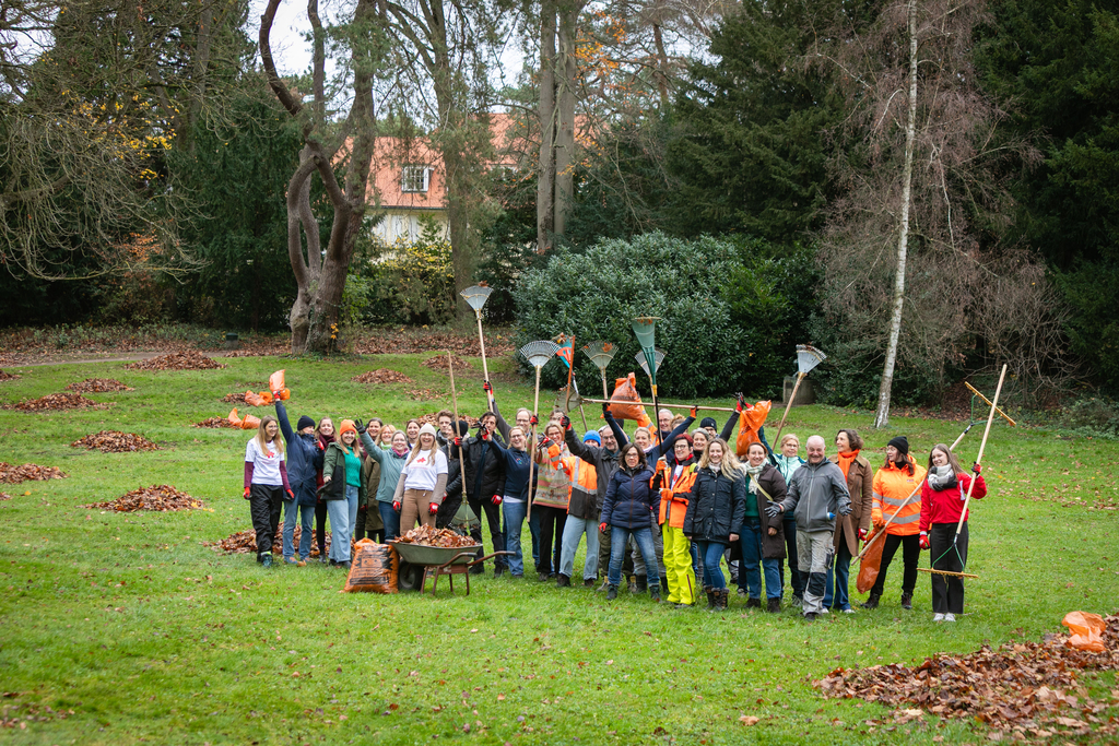 Personengruppe steht auf einer grünen Wiese im Park.