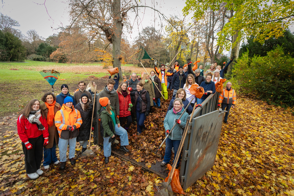 Personengruppe steht in einem mit Laub gefüllten Container.