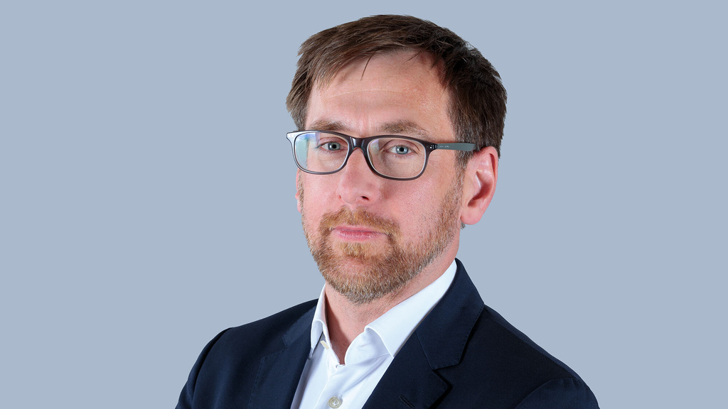 Mann mit Brille im Porträt aufgenommen.