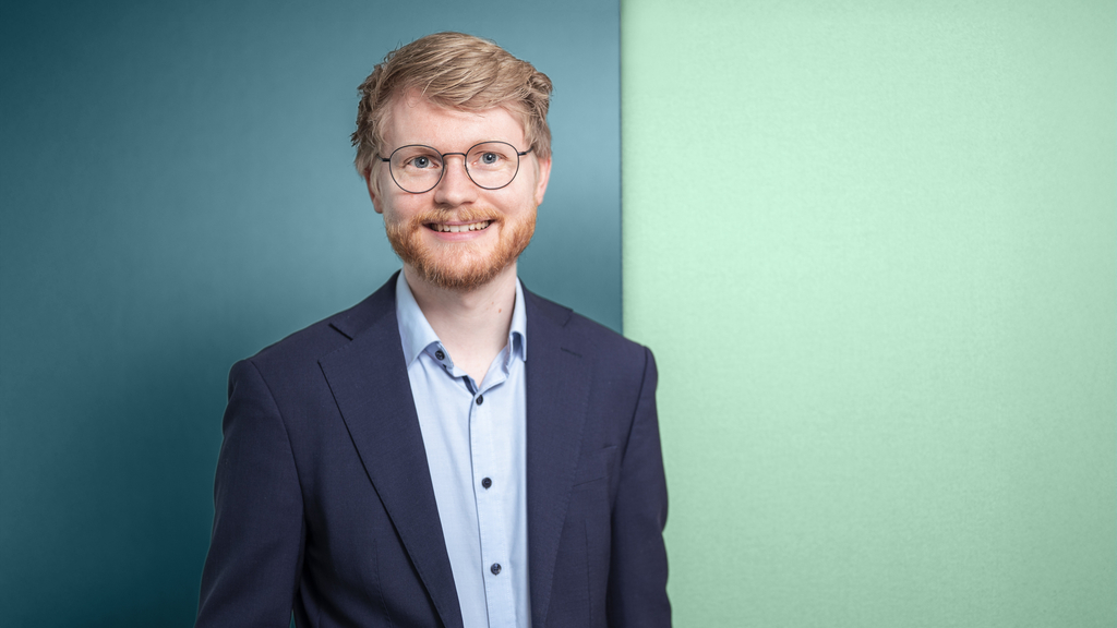 Mann mit Brille und Bart, im Portrait aufgenommen.