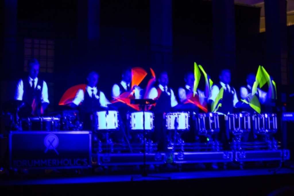 Mitglieder der Band "The Drummerholic´s" sitzt auf einer Bühne und spielt Schlagzeug.