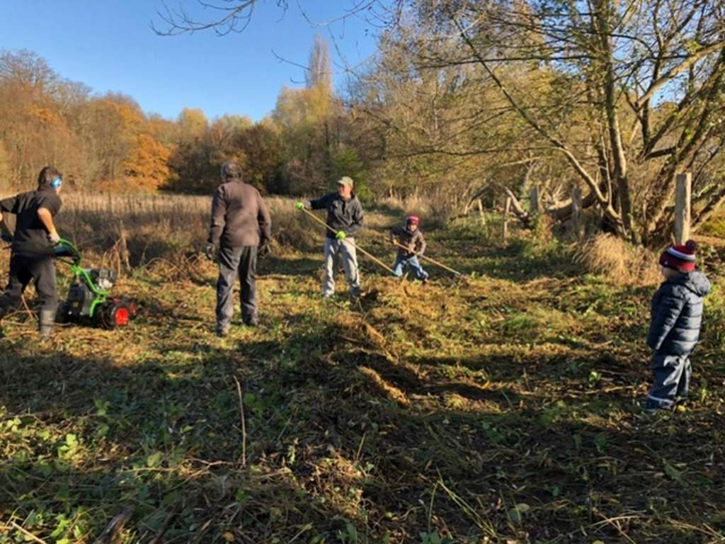 Drei Erwachsene und zwei Kinder bewirtschaften eine Wiese 