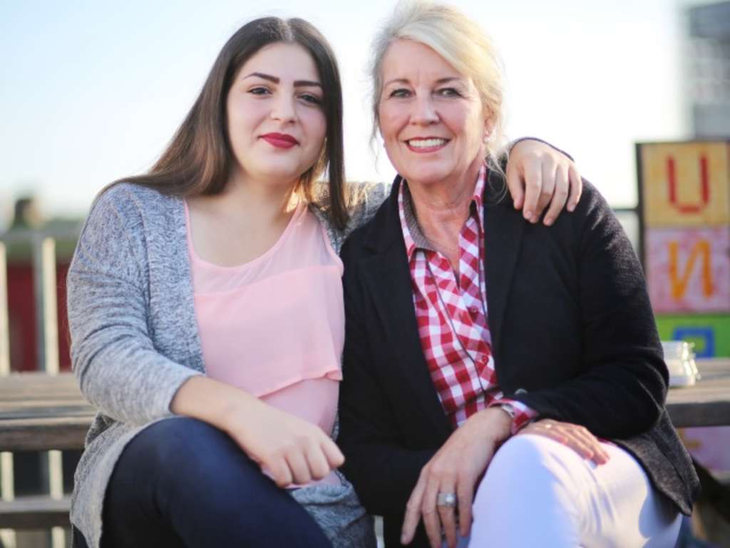 Jugendliches Mädchen legt den Arm um ihre Ausbildungspatin