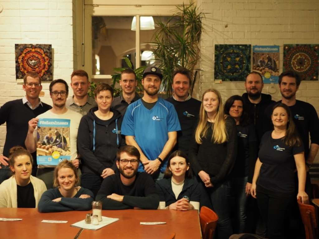 Gruppenfoto engagierter Ingenieurinnen und Ingenieuren bei einem Treffen. Ein Poster "#Wir BauenZusammen" wird hoch gehalten.