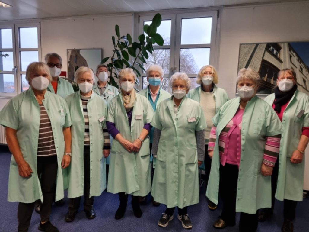 Gruppenfoto der "Grünen Damen", einheitlich gekleidet im hellgrünen Kittel und mit Mund-Nasen-Schutz