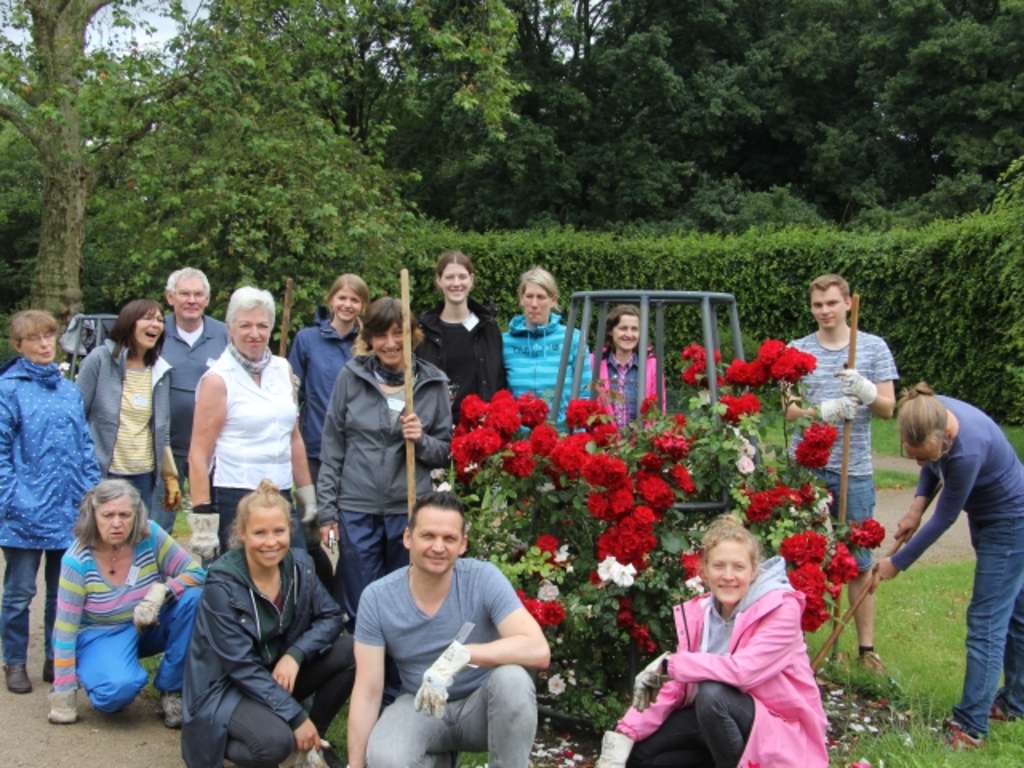 Das Rosengartenteam und die fleißigen Mitarbeitenden der Stadt Köln stehen im Rosengarten zusammen für ein Gruppenfoto.