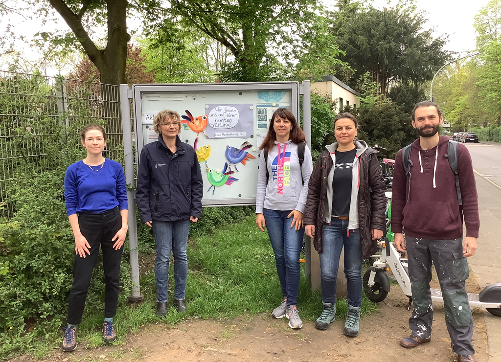 Gruppenbild mit fünf StadtAktiv-Teilnehmer*innen vor einem Schaukasten der Schule. 