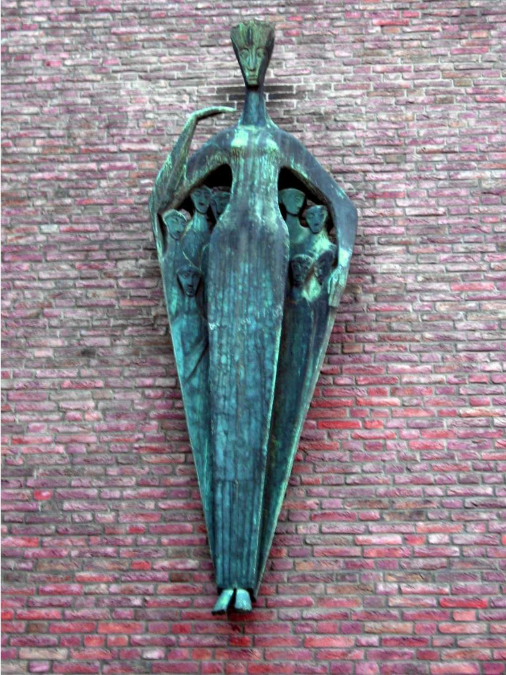 Foto der Bronze-Skulptur der Schutzpatronin Jungfrau Colonia an der Wand des Rathaus, Spanischer Bau. Unter ihren schützenden Armen sind fünf kleinere Skulpturen zu erkennen.