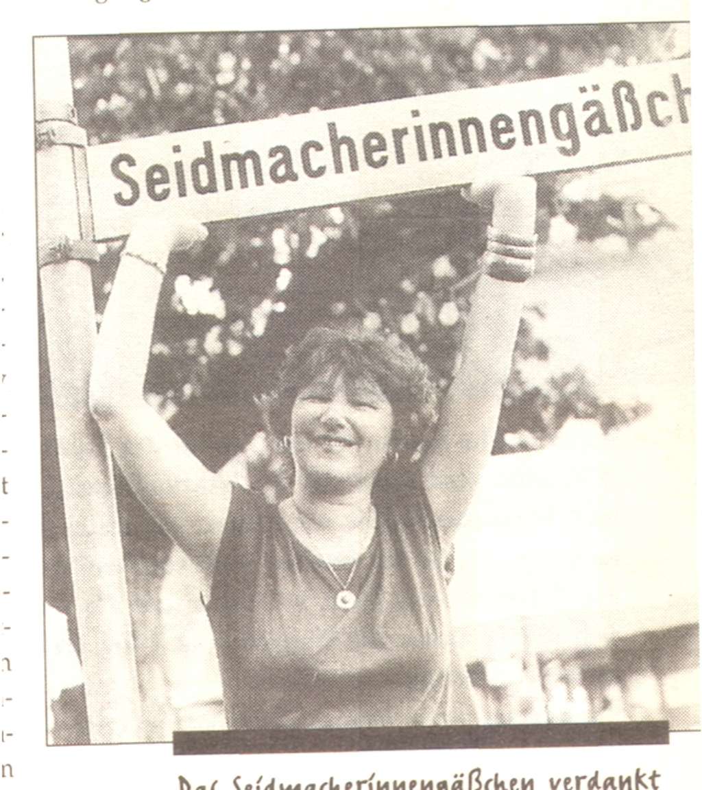 Foto eines Zeitungsbilds, eine Frau "stützt" lachend das Straßenschild des Seidmacherinnengäßchens
