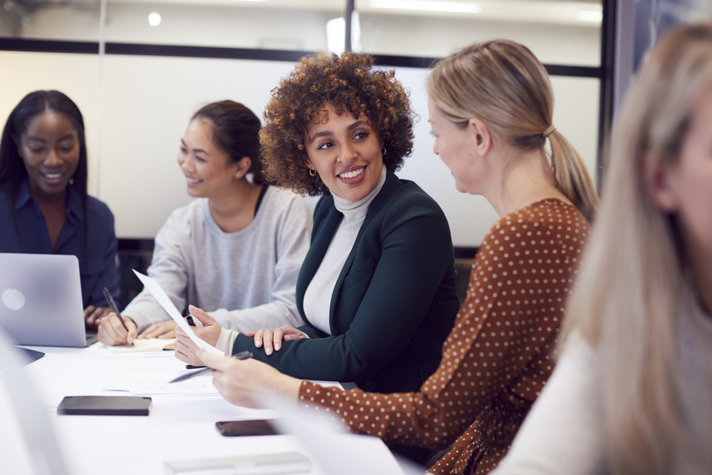 Gruppe von Geschäftsfrauen, die in einem modernen Büro an einem großen Tisch zusammenarbeiten. 