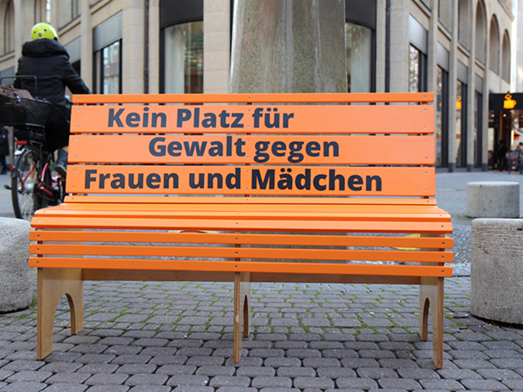 Aufgestellt orangene Bank mit dem Slogan "Kein Platz für Gewalt gegen Frauen und Mädchen"