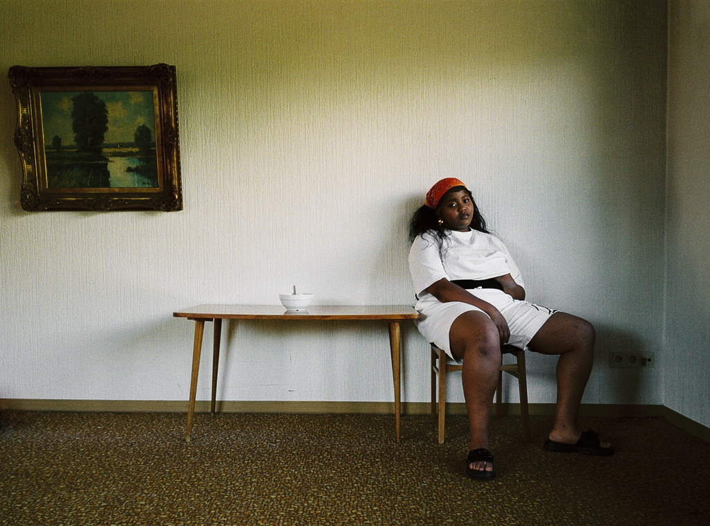 Bild von Ish in einem Wohnzimmer, sie sitzt auf einem Stuhl